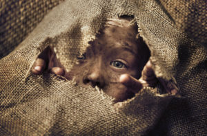 A homeless child hides in a sack. Photo © Konradbak - Dreamstime.com