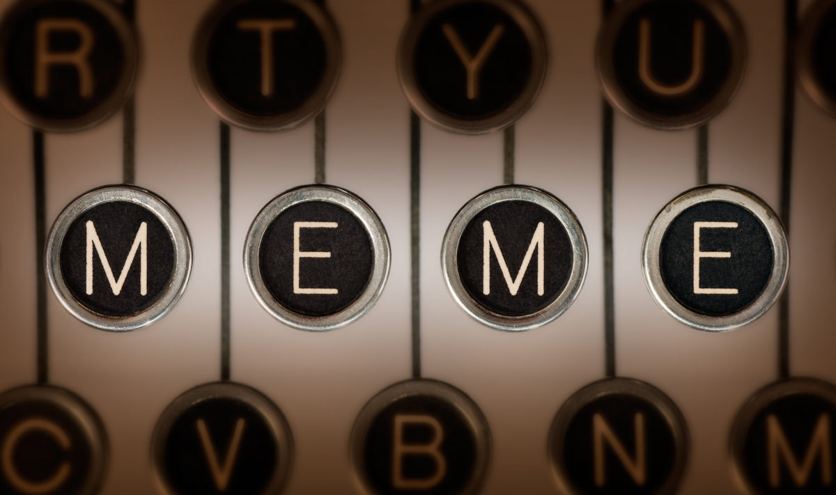 Close up of old typewriter keyboard with scratched chrome keys that spell out "MEME". Lighting and focus are centered on "MEME".