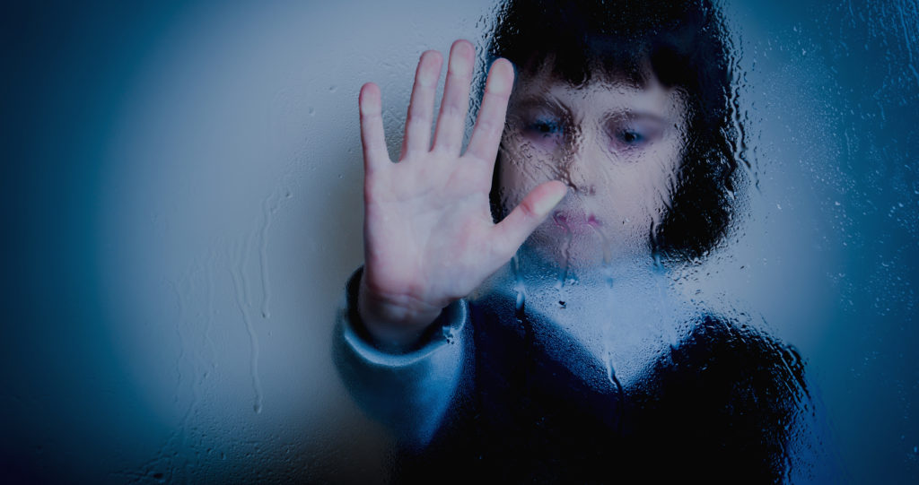 Photo of a young girl behind a glass pane showing the stop sign © Iurii Kuzo | Dreamstime.com
