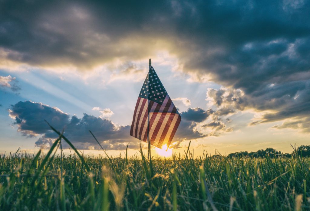 Representative photo of the USA flag on a grass field | Photo by Aaron Burden on Unsplash