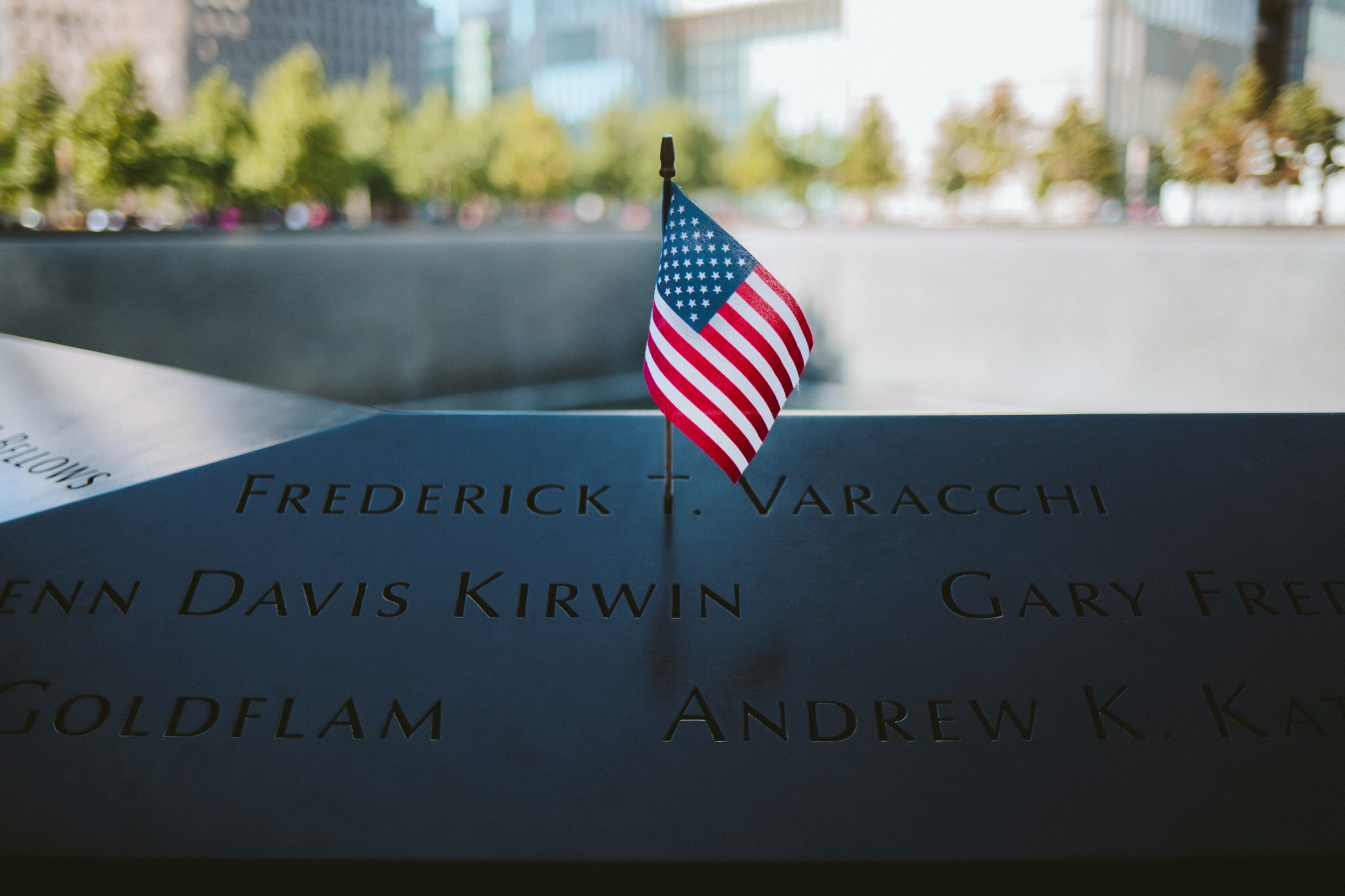 Representative image of an American flag against the backdrop of the the WTC 9/11 Memorial in New York City