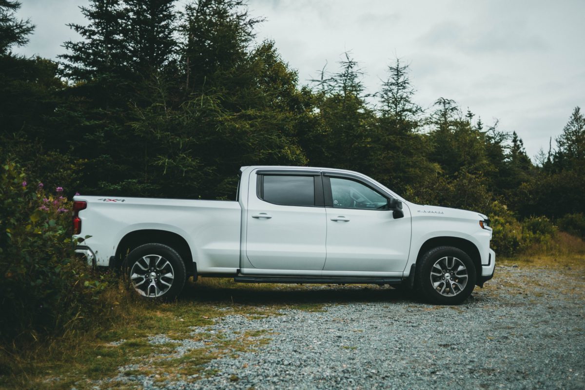 Representative photo of a white pickup truck parked amidst a backdrop of trees | Photo by Jonathan Cooper on Unsplash
