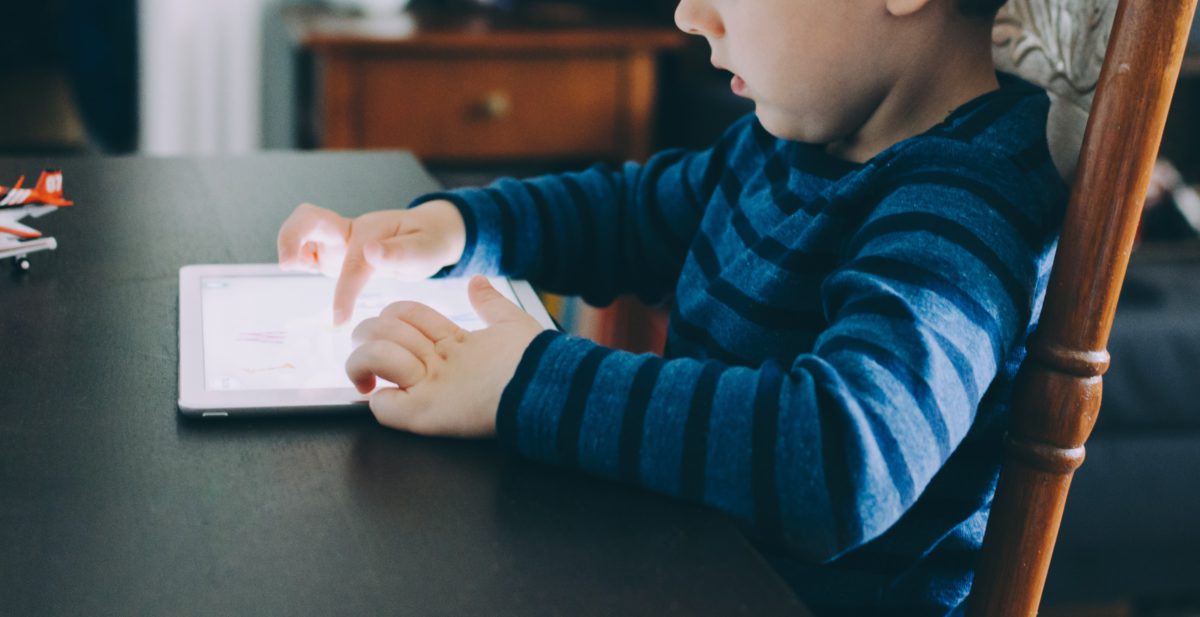 Representative photo of a boy sitting with a tablet at a table | Photo by Kelly Sikkema on Unsplash