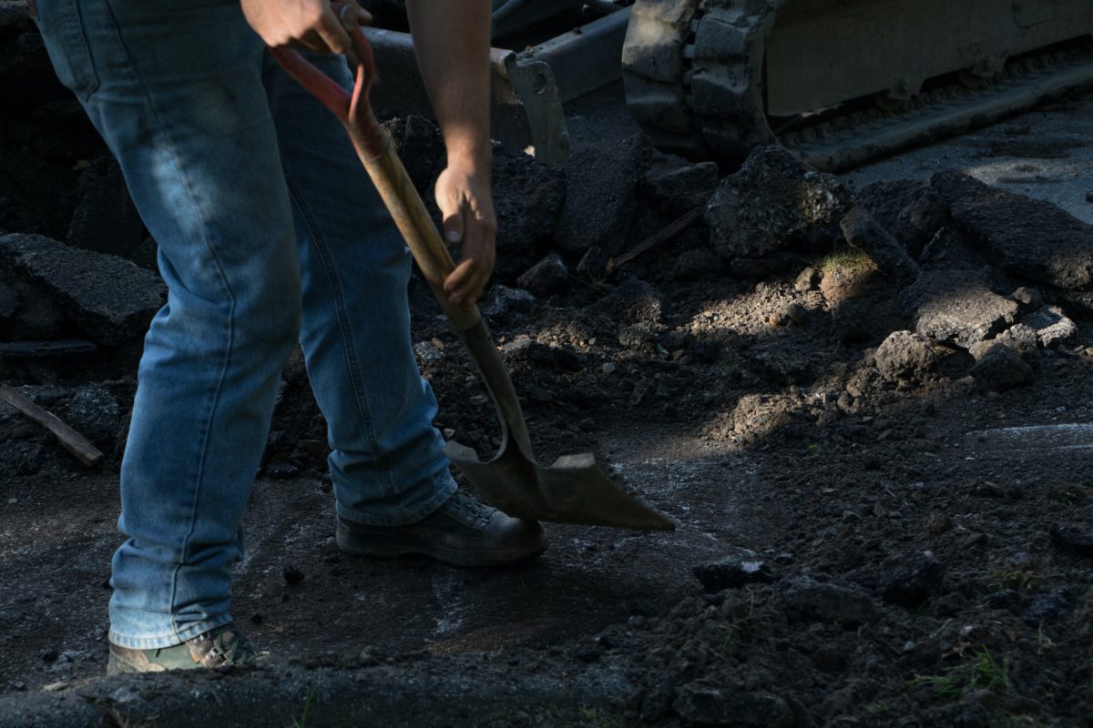 Representative image of labor, depicting the hands and legs of a person using a shovel at a construction site | Photo by Dylan Gillis on Unsplash