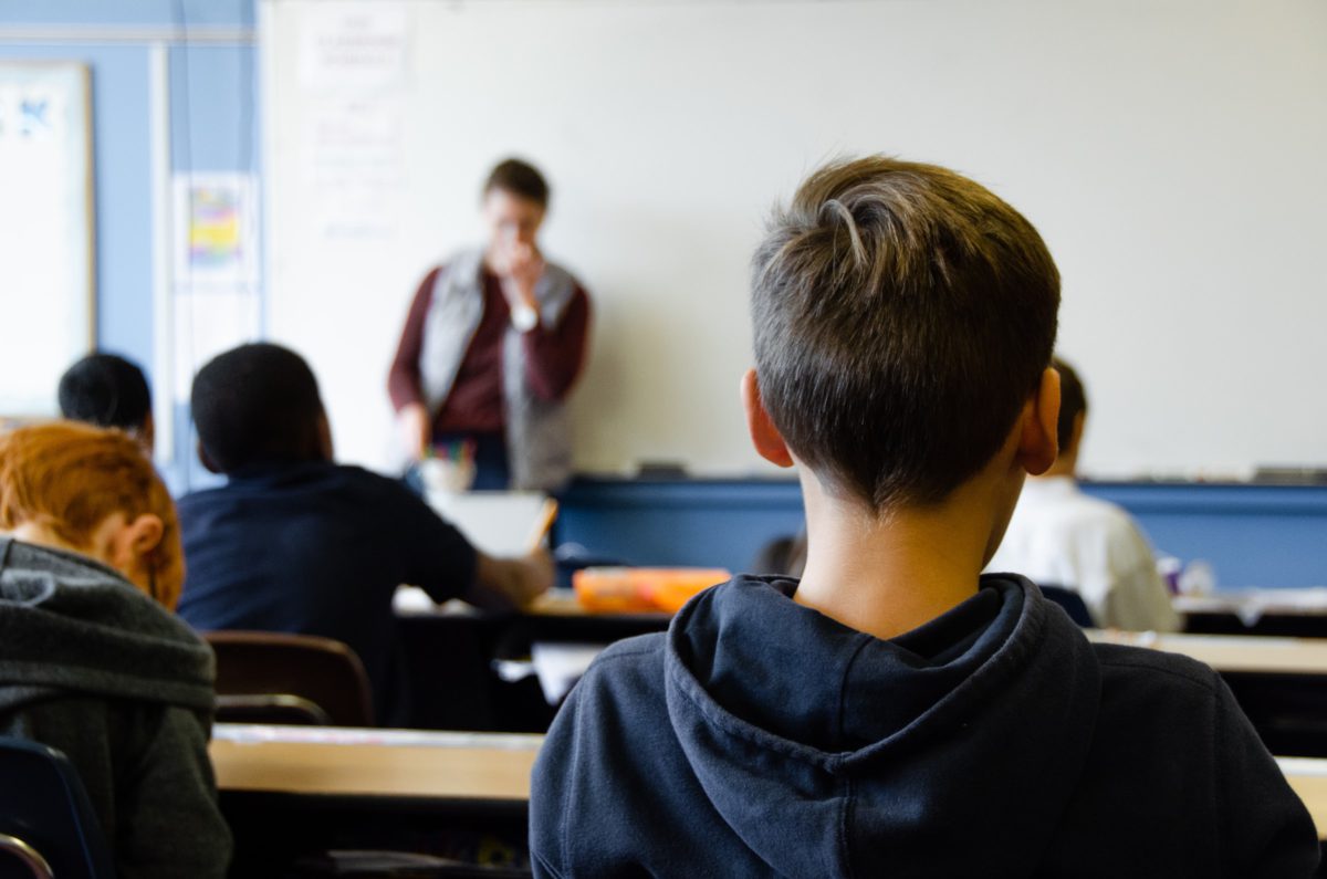 Photo of a school classroom shot from behind, showing rows of students. | Photo by Taylor Flowe on Unsplash