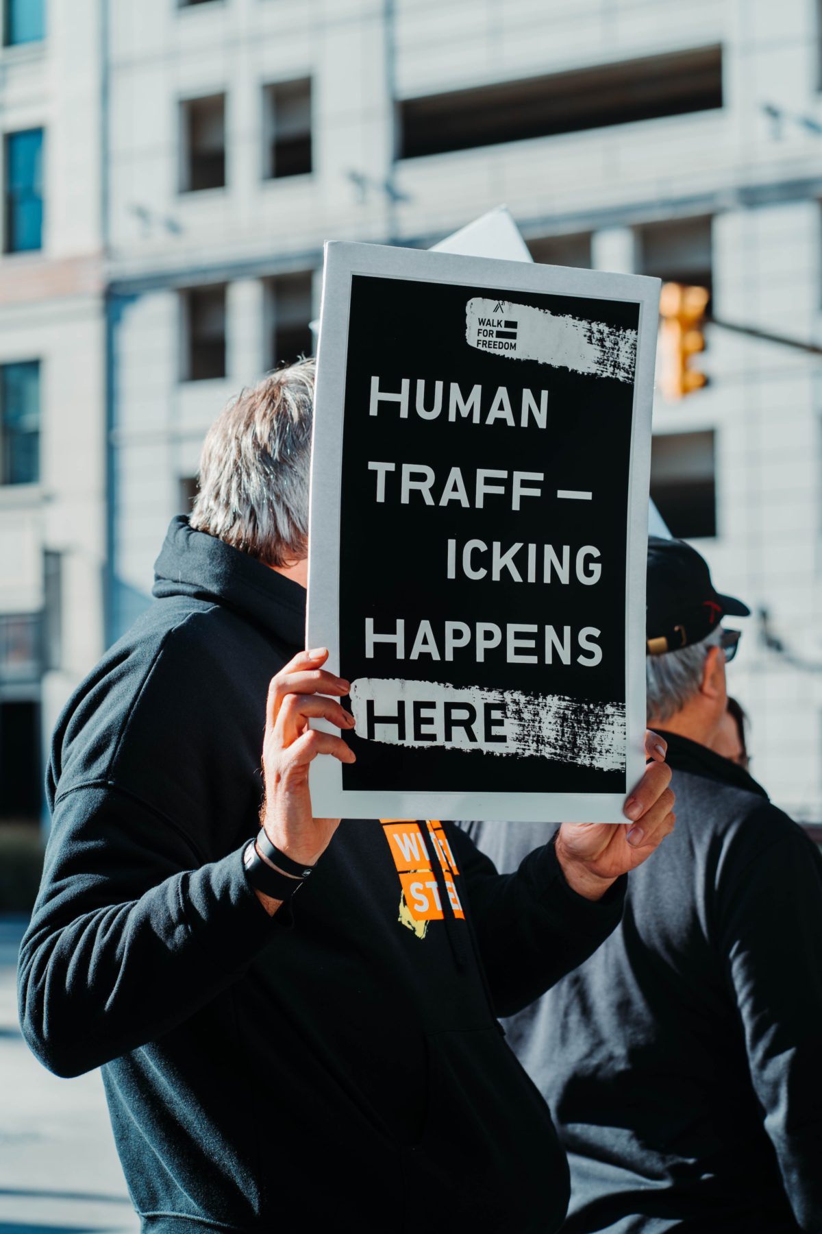 Man in black jacket holds up an anti-human trafficking sign at a demonstration. | Photo by Hermes Rivera on Unsplash